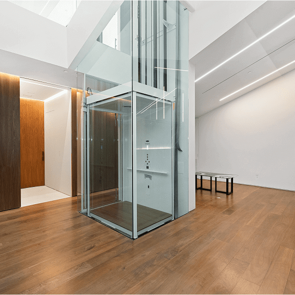 Modern interior with glass elevator and wood flooring.